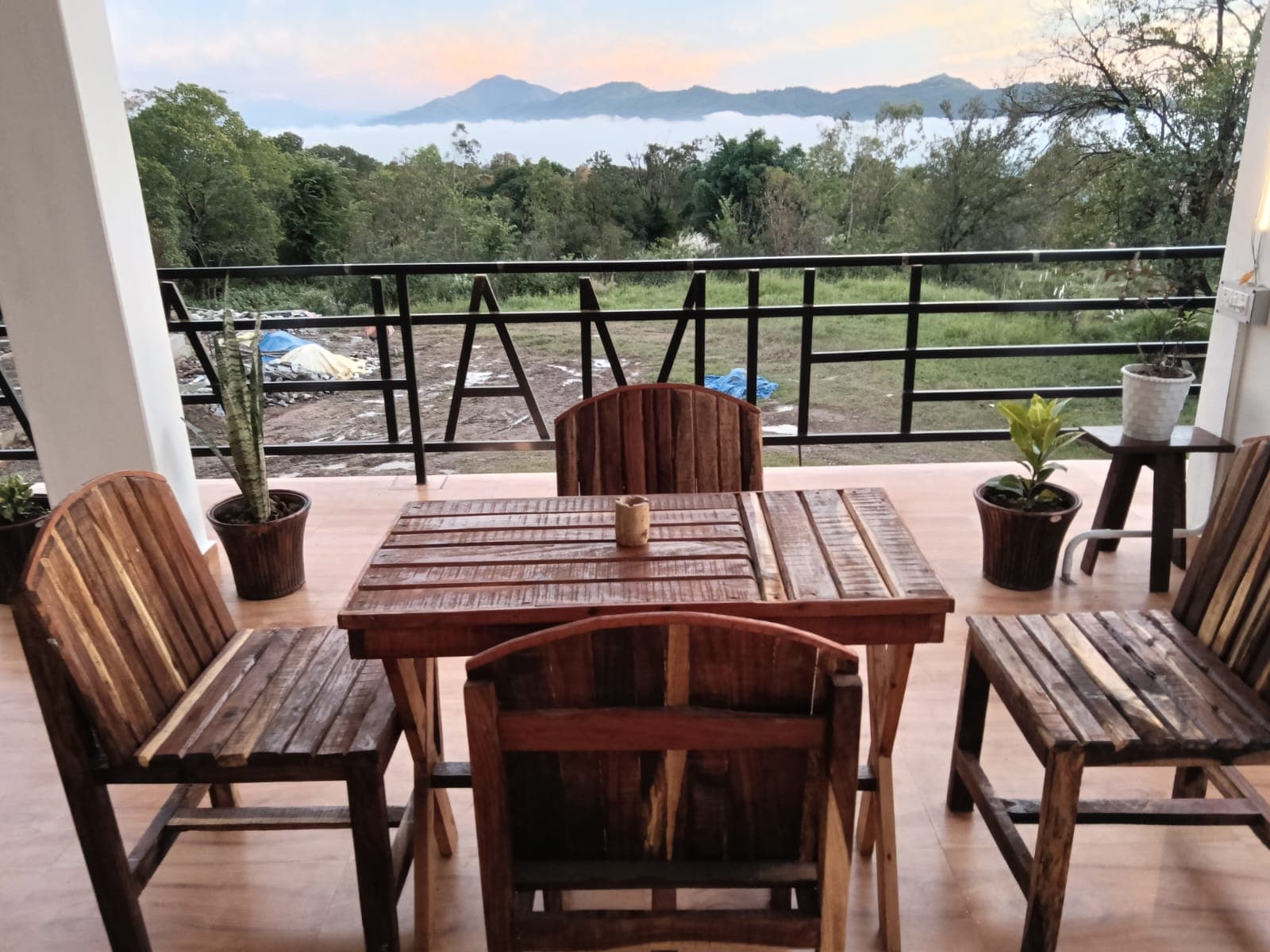 Wooden table and chairs on the balcony, looking out at mountains above a sea of morning clouds.