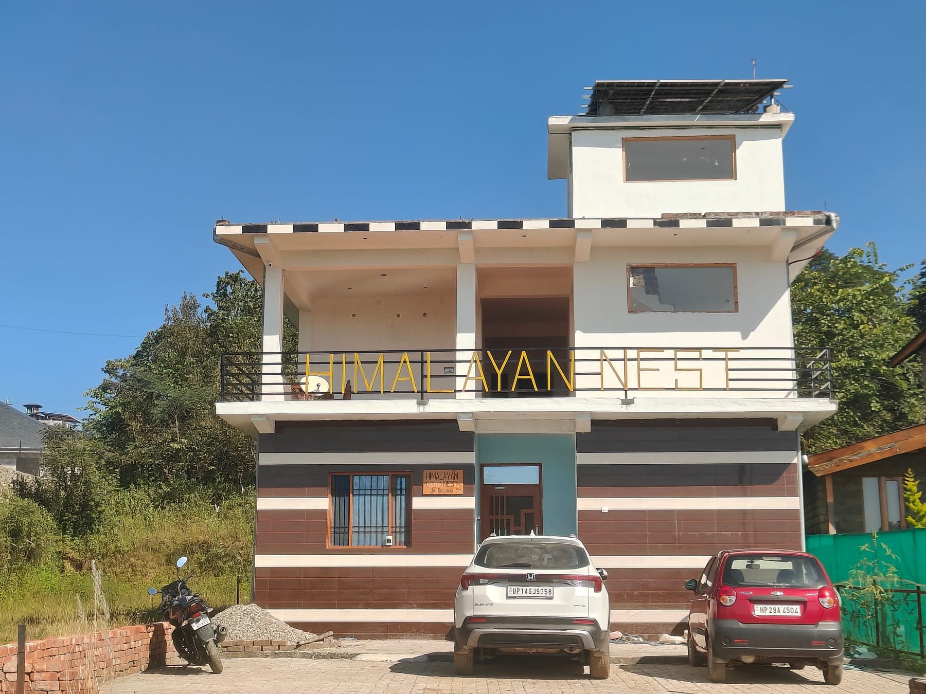 The Himalayan Nest building front, framed by mountains and blue sky.