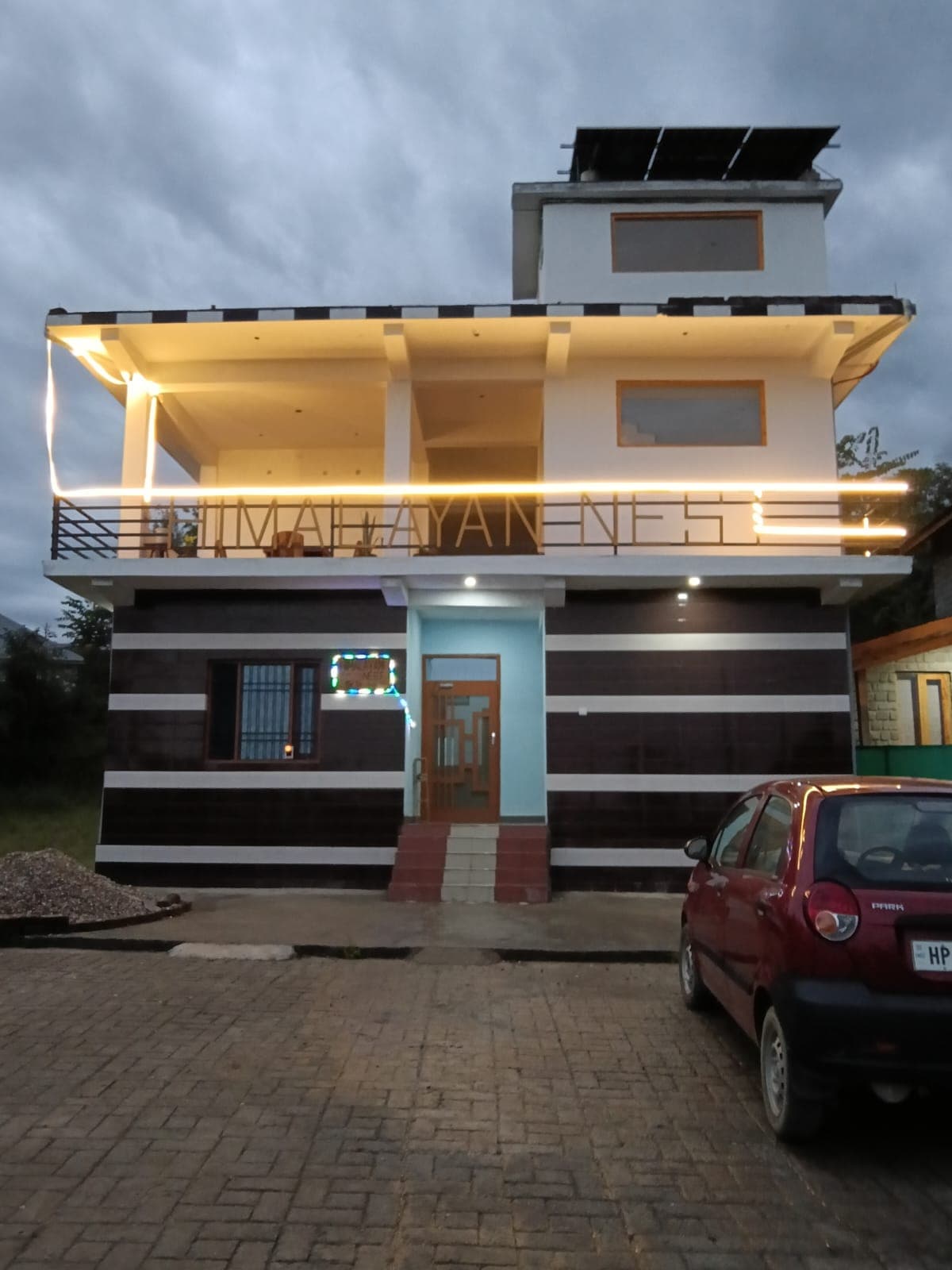 Himalayan Nest at dusk, with warm lights tracing the balcony's HIMALAYAN NEST railing.